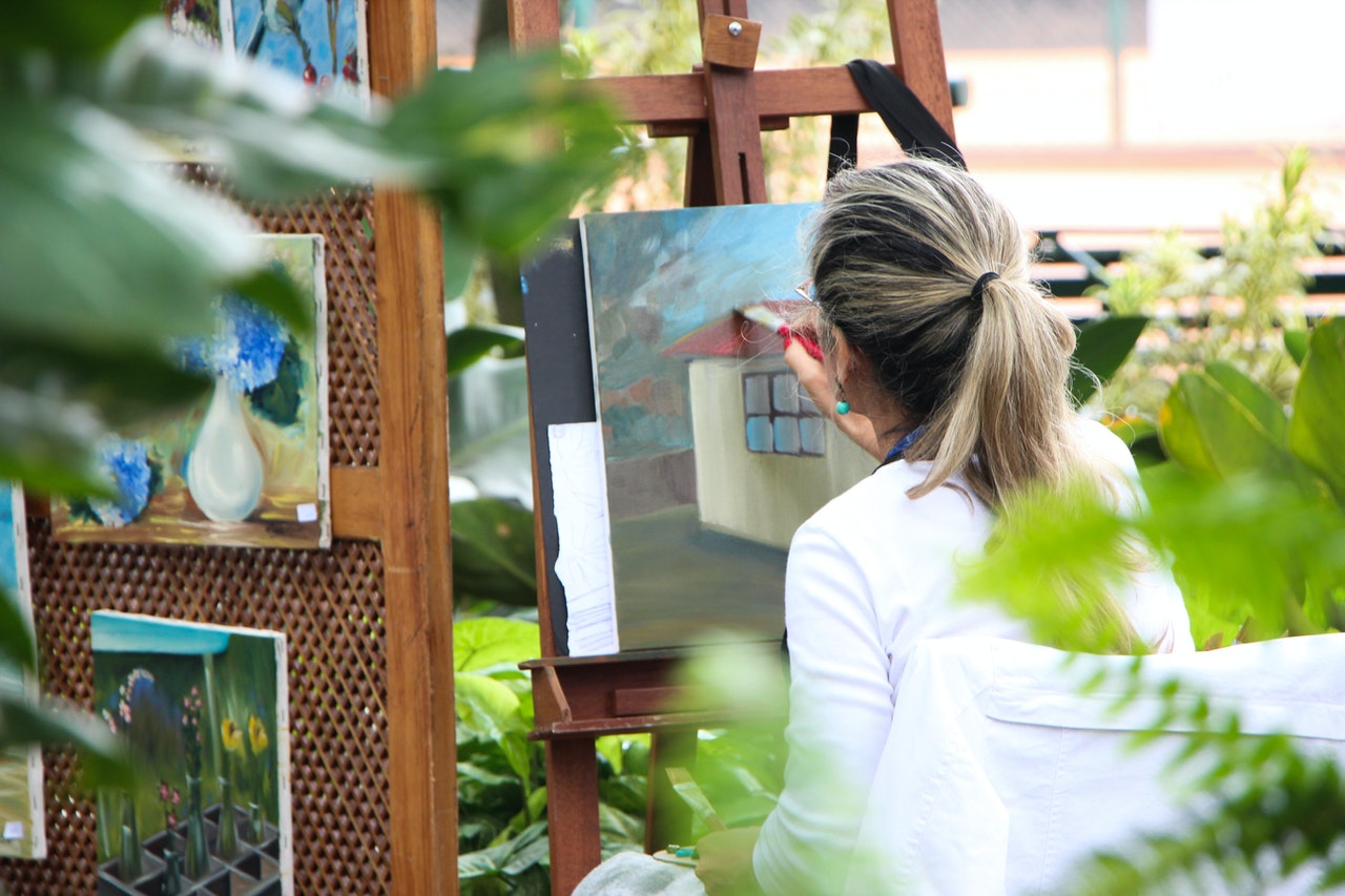 woman painting house outdoors in garden